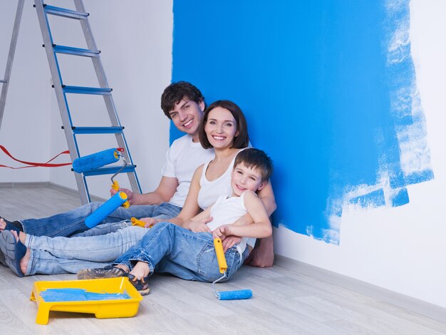 Retrato de uma jovem família feliz com o filho pequeno sentado perto da parede pintada