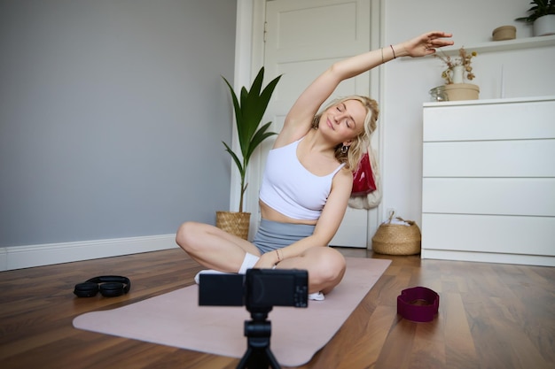 Foto grátis retrato de uma jovem fazendo ioga em casa blogueiro gravando vídeo em câmera digital enquanto trabalha