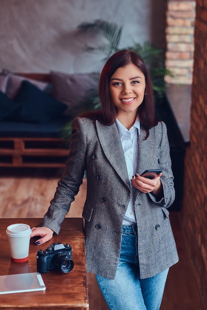 Retrato de uma jovem fotógrafa trabalha com um telefone leani