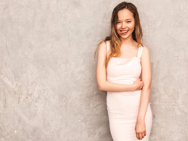 Retrato de uma jovem garota bonita e sorridente na moda verão luz vestido rosa. Mulher despreocupada sexy posando. Modelo positivo se divertindo e mostrando a língua