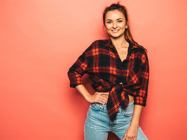 Retrato de uma jovem garota bonita sorridente hipster em roupas de verão jeans e camisa quadriculada na moda. mulher despreocupada 