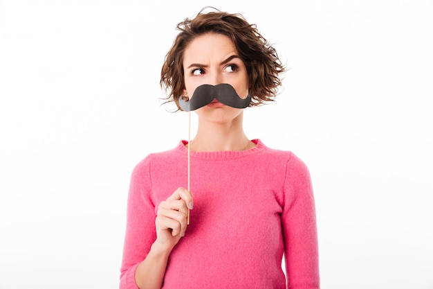 Retrato de uma jovem garota engraçada segurando bigodes de papel