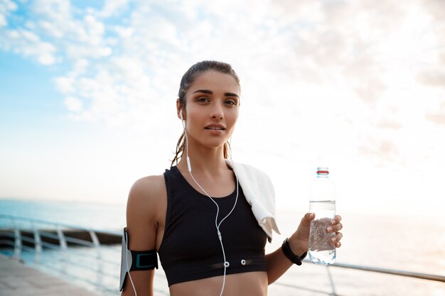 Retrato de uma jovem garota esportiva bonita ao nascer do sol sobre a beira-mar.