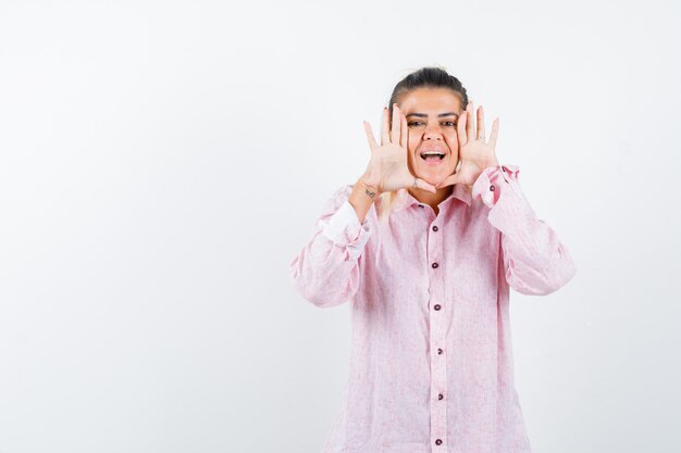 Retrato de uma jovem gritando ou anunciando algo em uma camisa rosa e olhando frontalmente feliz