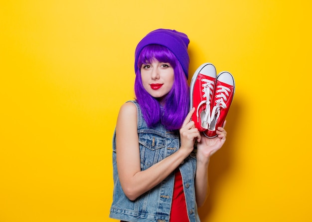 Retrato de uma jovem hipster com cabelo roxo e sapatos vermelhos em fundo amarelo