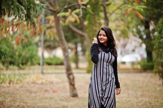 Retrato de uma jovem linda indiana ou adolescente do sul da Ásia em vestido posado no parque de outono na Europa