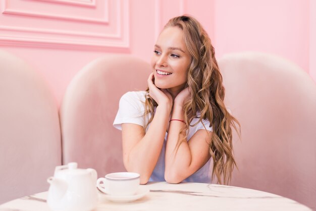 Retrato de uma jovem linda mulher bebendo chá em um café moderno durante o intervalo do trabalho