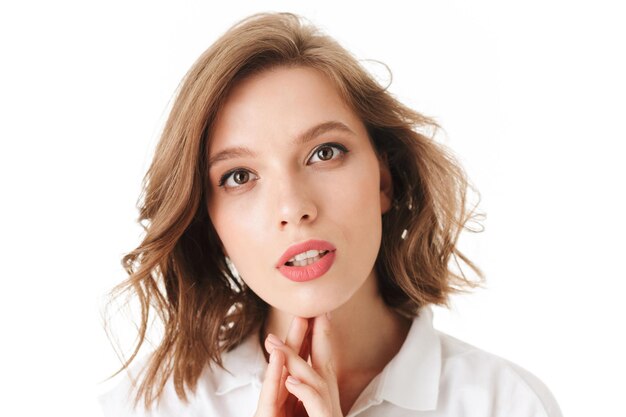 Retrato de uma jovem linda mulher sonhadoramente olhando para a câmera em fundo branco isolado