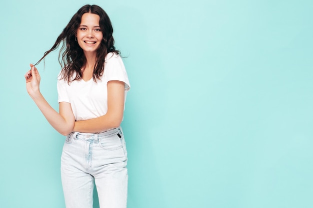 Retrato de uma jovem linda mulher sorridente em roupas da moda de verão Mulher despreocupada sexy posando perto da parede azul no estúdio Modelo positivo se divertindo dentro de casa Alegre e feliz