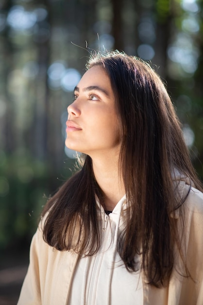 Foto grátis retrato de uma jovem linda na floresta. mulher caucasiana com cabelos escuros e olhos verdes, olhando para cima. retrato, natureza, conceito de beleza