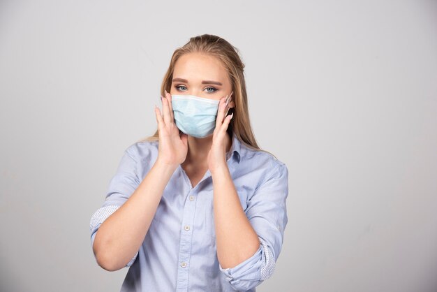 Retrato de uma jovem loira em pé com uma máscara médica