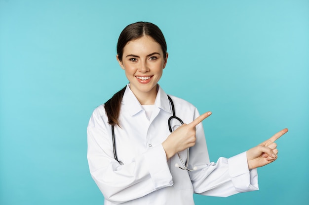 Retrato de uma jovem médica profissional trabalhadora hospitalar apontando os dedos para a direita mostrando o logotipo clin...