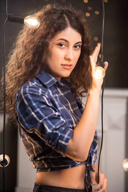 Retrato de uma jovem modelo em camisa xadrez posando perto de lâmpadas