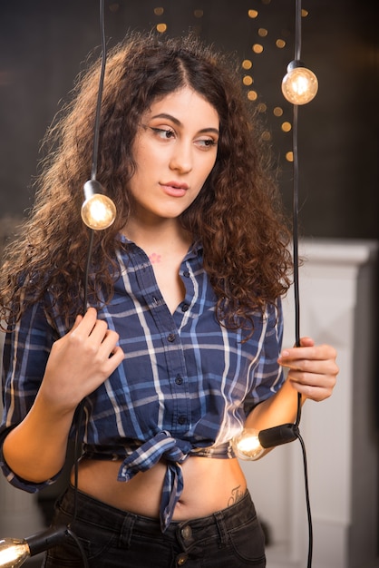 Foto grátis retrato de uma jovem modelo em camisa xadrez posando perto de lâmpadas