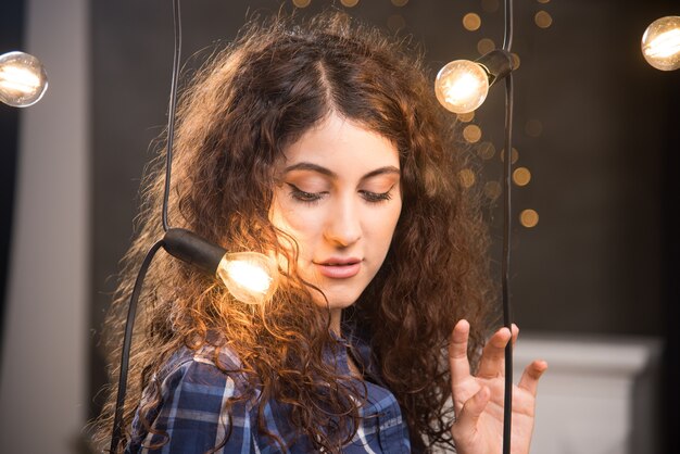 Retrato de uma jovem modelo em camisa xadrez posando perto de lâmpadas