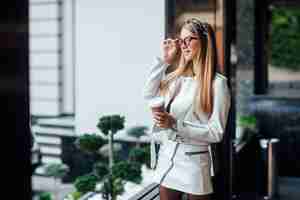 Foto grátis retrato de uma jovem modelo loira andando na cidade, garota com roupa elegante.