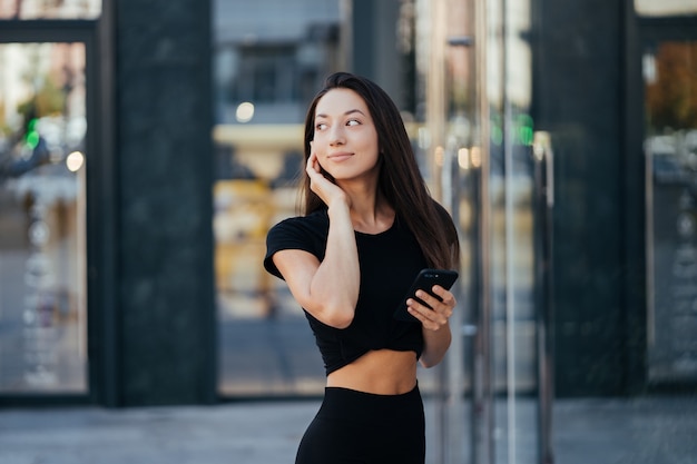 Retrato de uma jovem morena com fones de ouvido e sorrindo enquanto caminha