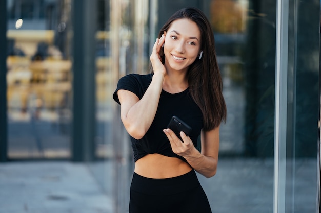 Retrato de uma jovem morena com fones de ouvido e sorrindo enquanto caminha