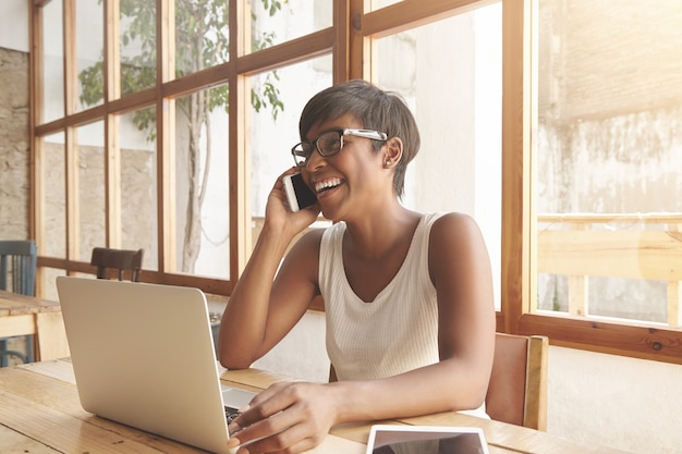 Foto grátis retrato de uma jovem morena sentada em um café com um laptop