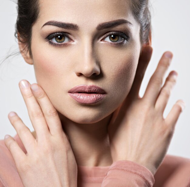 Retrato de uma jovem mulher bonita com maquiagem olhos esfumaçados. Muito jovem adulta posando Closeup rosto feminino atraente. Conceito de cuidados com a pele