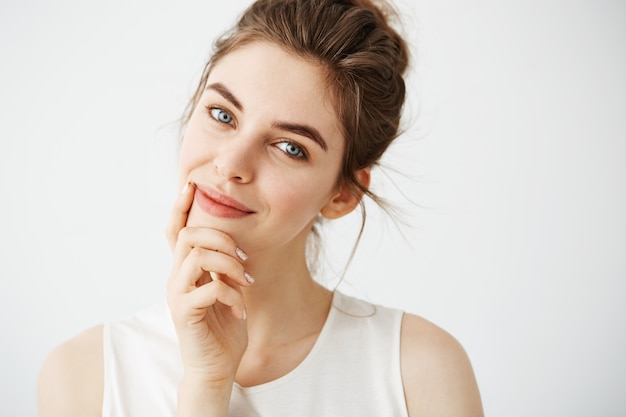 Retrato de uma jovem mulher bonita concurso com coque sorrindo tocando o rosto