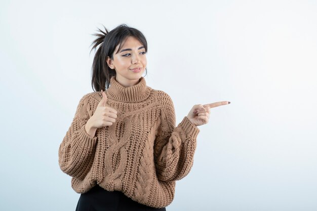 Retrato de uma jovem mulher bonita em malhas mostrando os polegares para cima