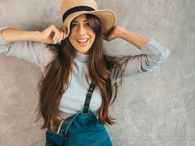 Retrato de uma jovem mulher bonita olhando. Menina na moda em roupas de verão casual macacão e chapéu.