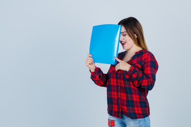 Retrato de uma jovem mulher bonita segurando a pasta em uma camisa casual, jeans