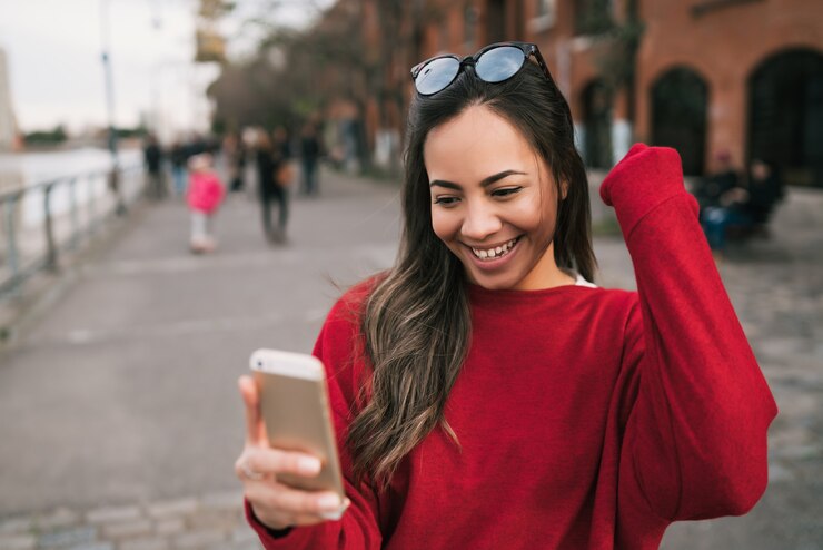 Foto grátis retrato de uma jovem mulher bonita segurando seu telefone celular com expressão de sucesso, celebrando algo. conceito de sucesso.