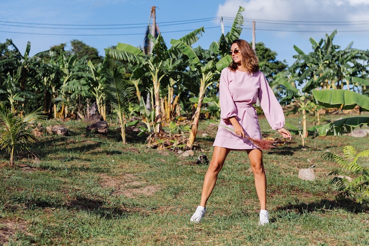 Foto grátis retrato de uma jovem mulher bronzeada caucasiana em um vestido rosa romântico, pulseira de prata com brincos redondos e óculos escuros