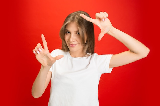 Retrato de uma jovem mulher caucasiana com emoções brilhantes em vermelho brilhante