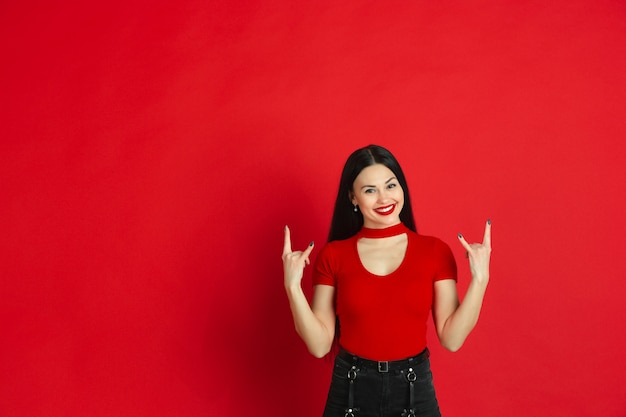 Retrato de uma jovem mulher caucasiana com emoções brilhantes sobre fundo vermelho studio