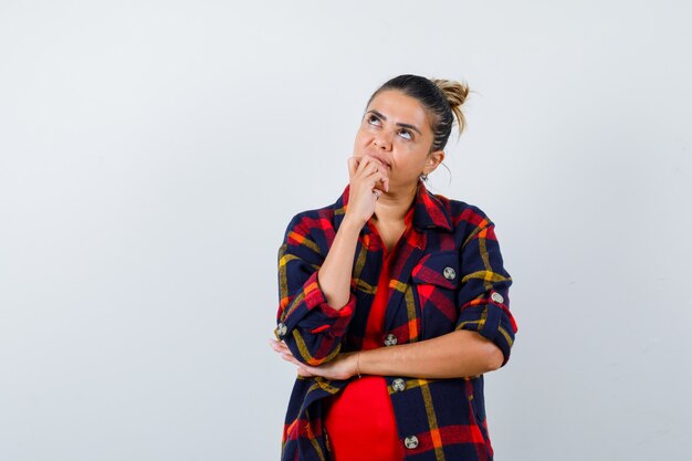 Retrato de uma jovem mulher em pose pensativa com uma camisa quadriculada e olhando pensativa para a frente