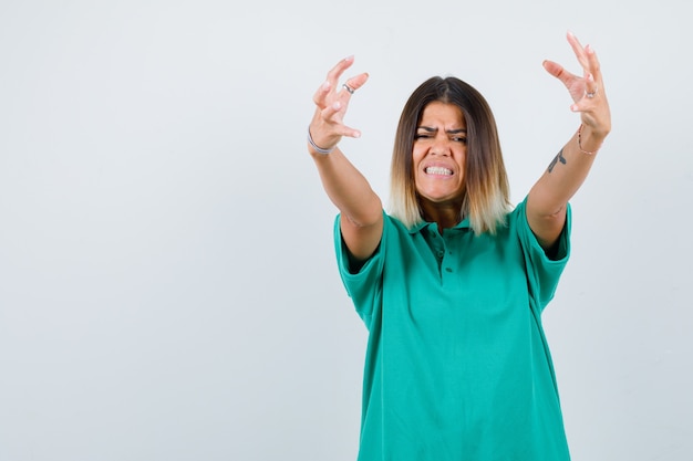 Foto grátis retrato de uma jovem mulher mostrando garras imitando um gato em uma camiseta polo e olhando agressivamente de frente