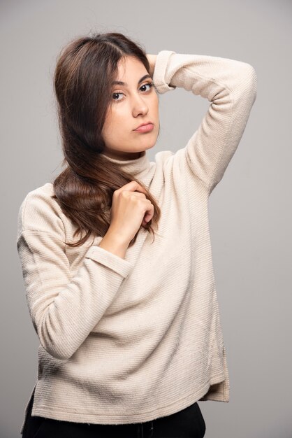 Retrato de uma jovem mulher posando em uma parede cinza.