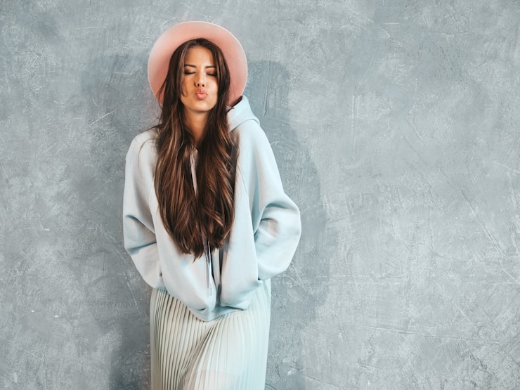 Foto grátis retrato de uma jovem mulher sorridente bonita olhando. menina na moda em roupas de verão casual capuz e saia. dando beijo no ar