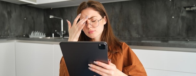 Foto grátis retrato de uma jovem que se sente mal tocando a cabeça tem dor de cabeça ou enxaqueca lendo em digital