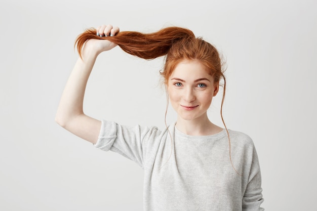 Retrato de uma jovem ruiva linda tocando seu rabo de cabelo.