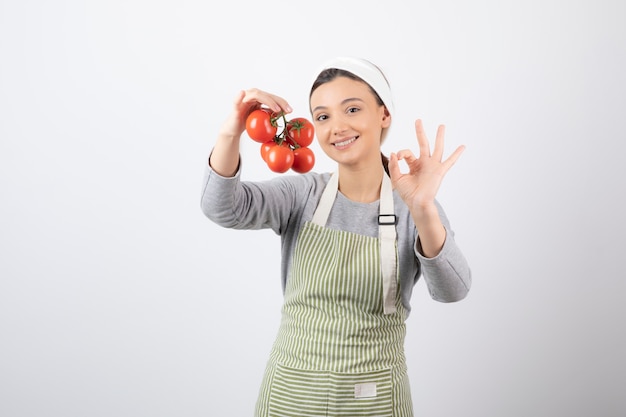 Retrato de uma jovem segurando tomates vermelhos sobre uma parede branca