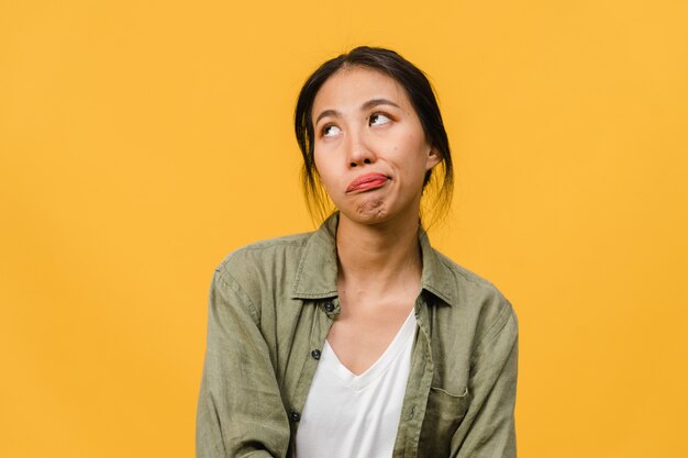 Retrato de uma jovem senhora asiática com expressão negativa, animado, gritando, chorando com raiva emocional em roupas casuais, isolado na parede amarela com espaço de cópia em branco. Conceito de expressão facial.