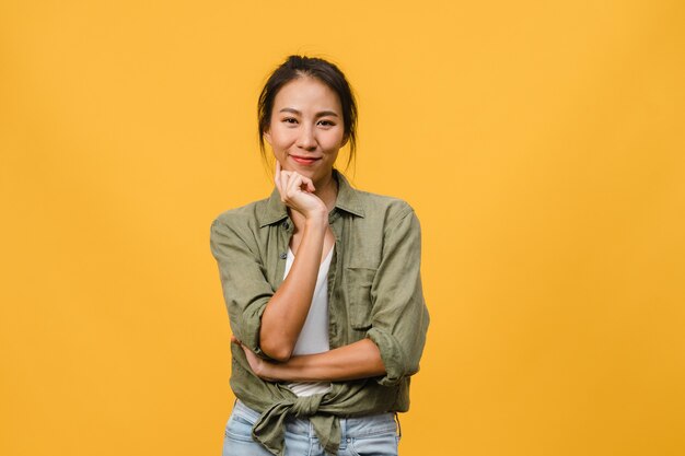 Retrato de uma jovem senhora asiática com expressão positiva, braços cruzados, sorriso largo, vestida com roupas casuais sobre parede amarela. Mulher feliz adorável feliz alegra sucesso.