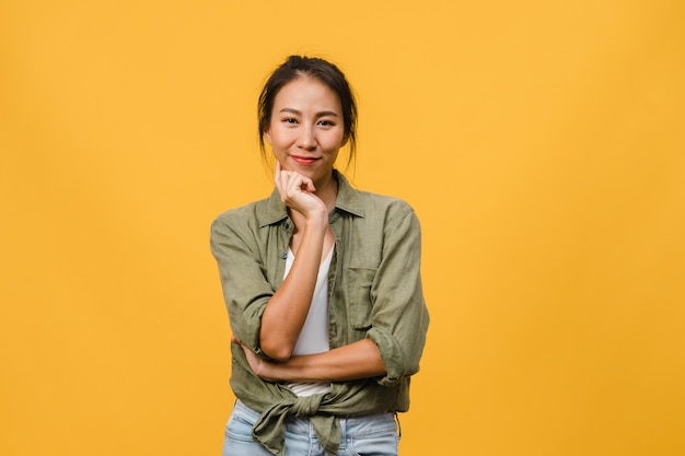 Retrato de uma jovem senhora asiática com expressão positiva, braços cruzados, sorriso largo, vestida com roupas casuais sobre parede amarela. Mulher feliz adorável feliz alegra sucesso.