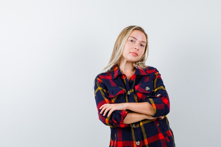 Foto grátis retrato de uma jovem senhora em pé com os braços cruzados em uma camisa xadrez e com uma vista frontal confiante