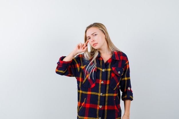 Retrato de uma jovem senhora em pose pensativa com uma camisa quadriculada e com uma vista frontal confiante