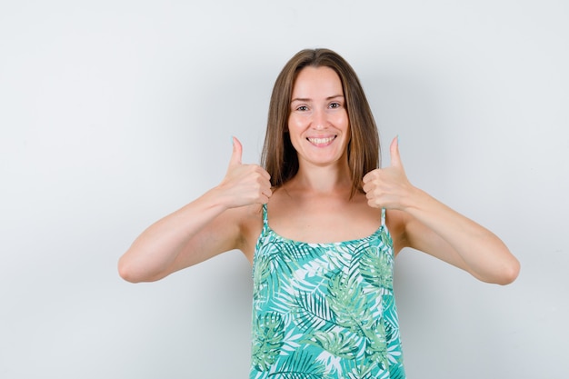 Retrato de uma jovem senhora mostrando os polegares para cima e olhando de frente com uma cara feliz