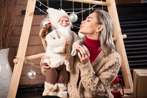 Retrato de uma jovem sentada no chão segurando um brinquedo de Papai Noel. Foto de alta qualidade.