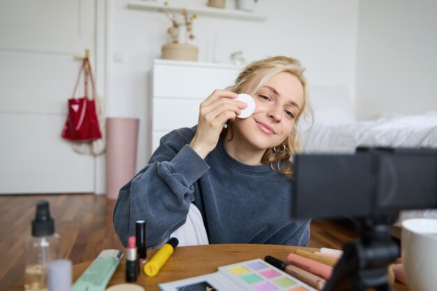 Retrato de uma jovem sorridente aplicando maquiagem mostra tutorial de beleza em registros de vídeo vlog em
