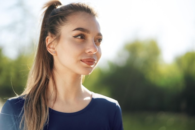 Retrato de uma jovem sorridente, vestindo roupas esportivas no parque matinal