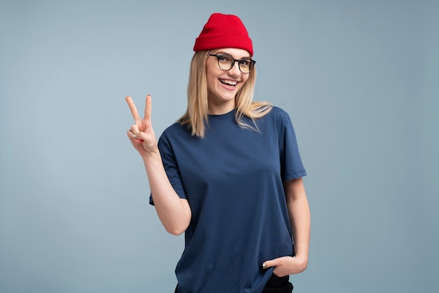 Foto grátis retrato de uma jovem sorrindo e mostrando o sinal de paz