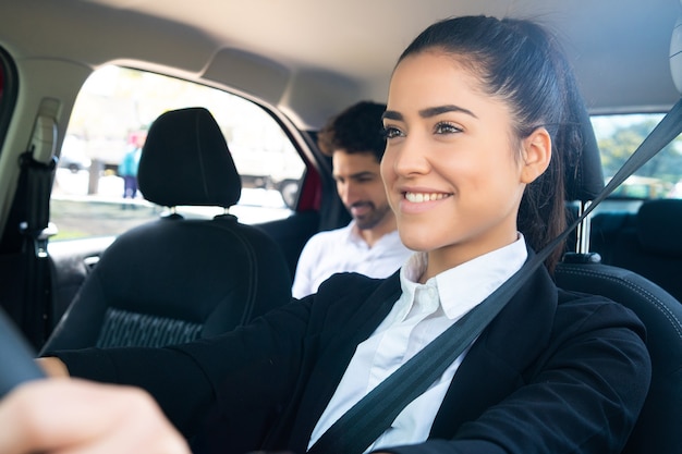 Foto grátis retrato de uma jovem taxista com um passageiro empresário no banco de trás